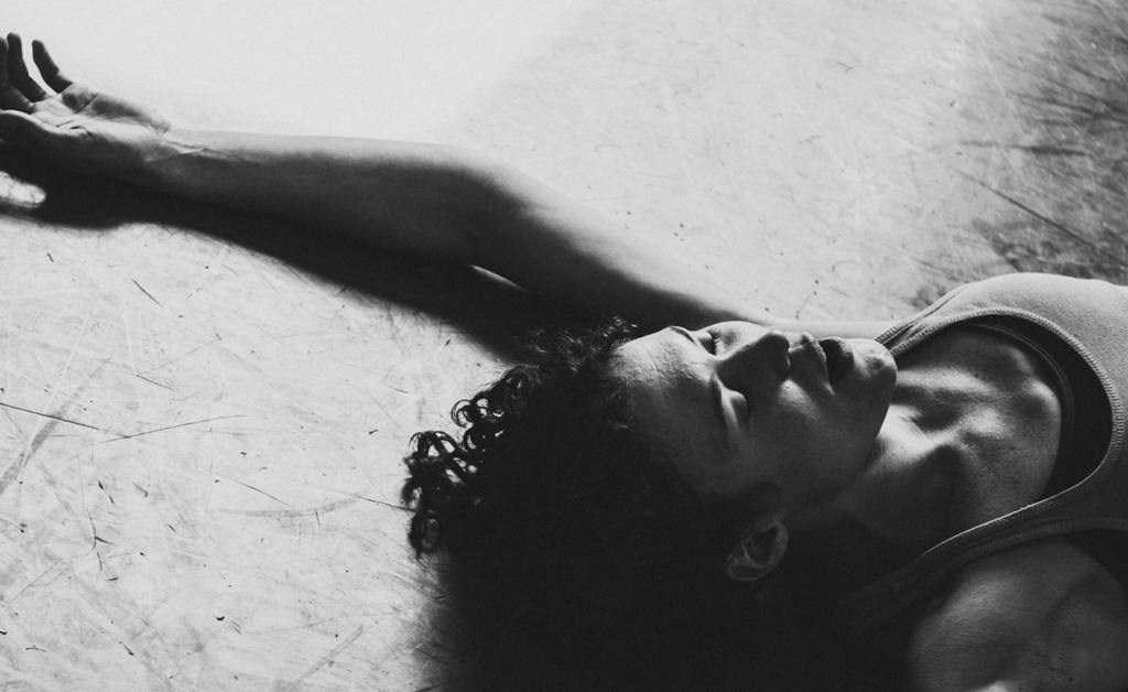 A black and white photo of Amy laying one the floor, eyes closed.