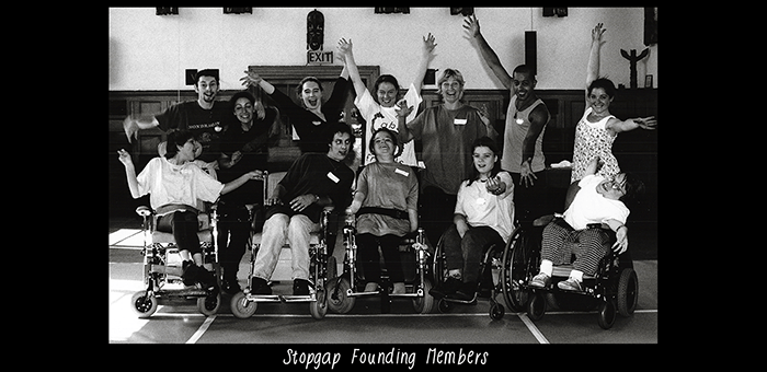 A black and white photo of an excited group posing for the camera. In white text along the bottom of the image is the title ‘Stopgap Founding Members’.