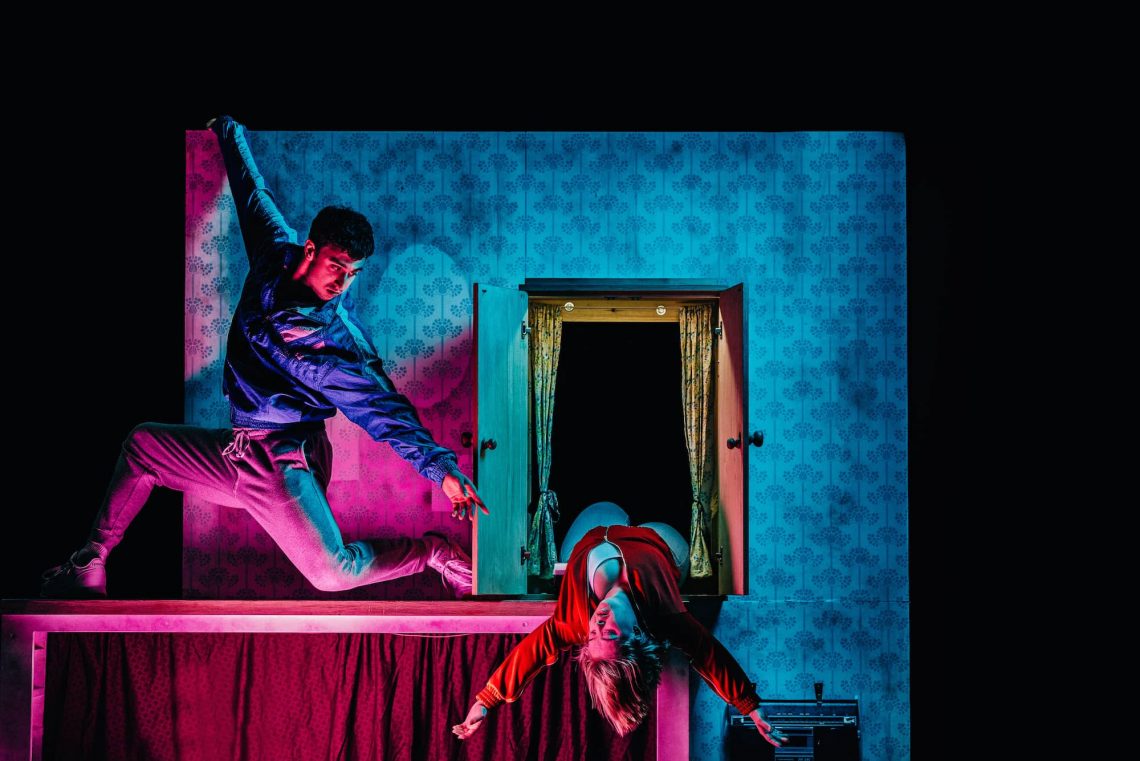 Photo from The Enormous Room - Christian reaches towards Hannah as she leans out from an open cupboard.