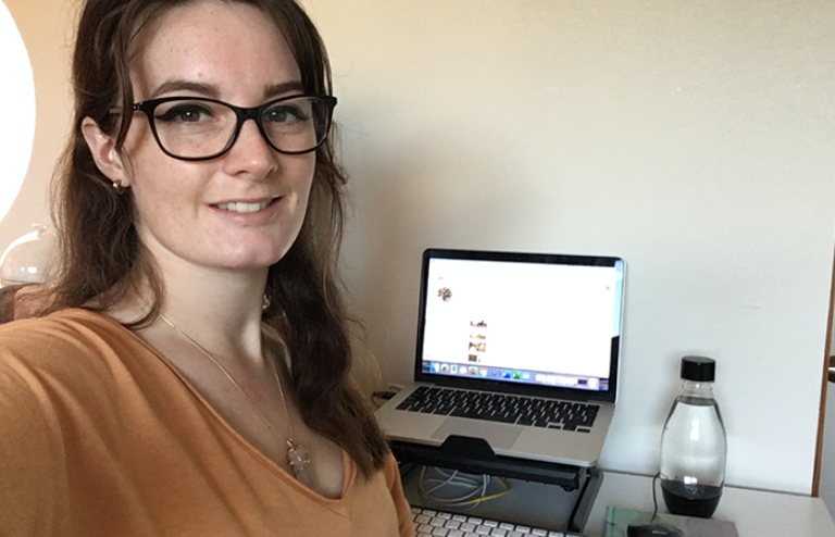 Anna sitting in front of her laptop, turned towards the camera and smiling.