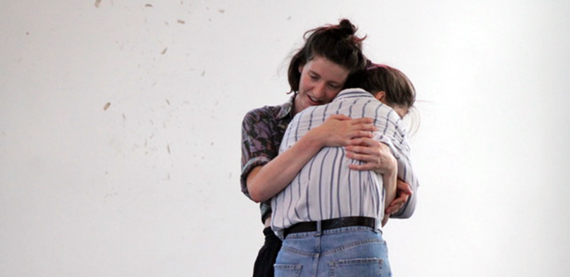 Lauren wraps her hands around another dancer, hugging them close to her.