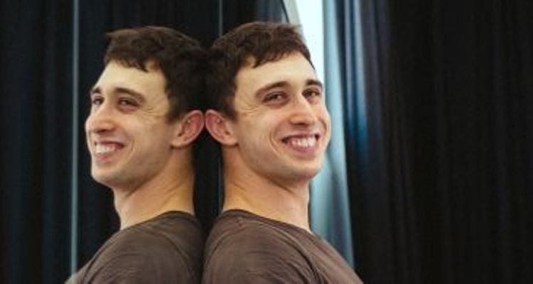 Portrait of Christian Brinklow, leaning with his back against a mirror and smiling into the camera