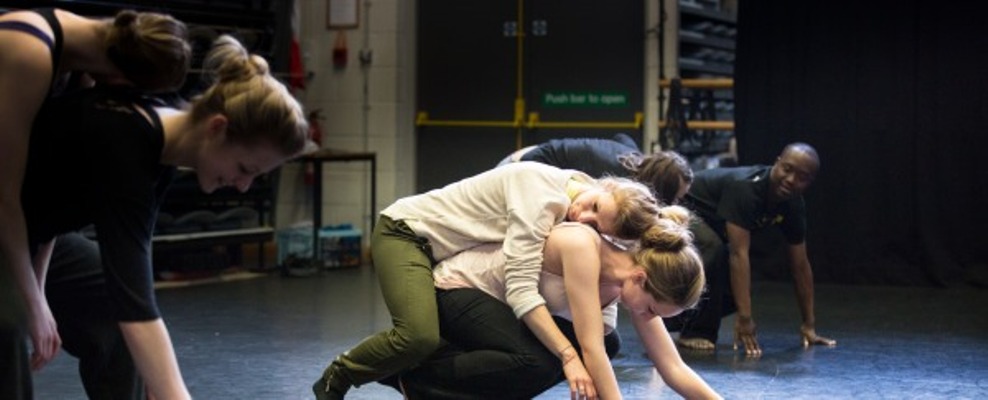 A pair of dancers, one crouching on the floor, the other relaxing over her shoulder and back