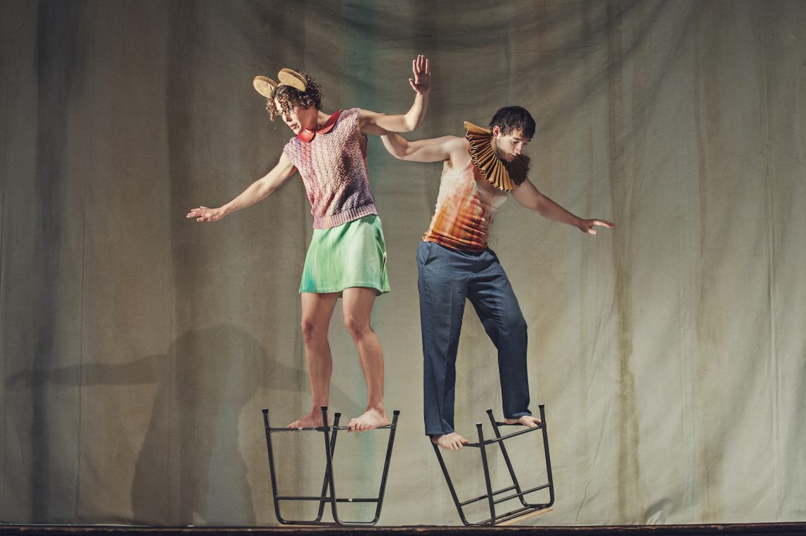 A photo from Artificial Things (2014) with two standing dancers balanced on upturned stools.