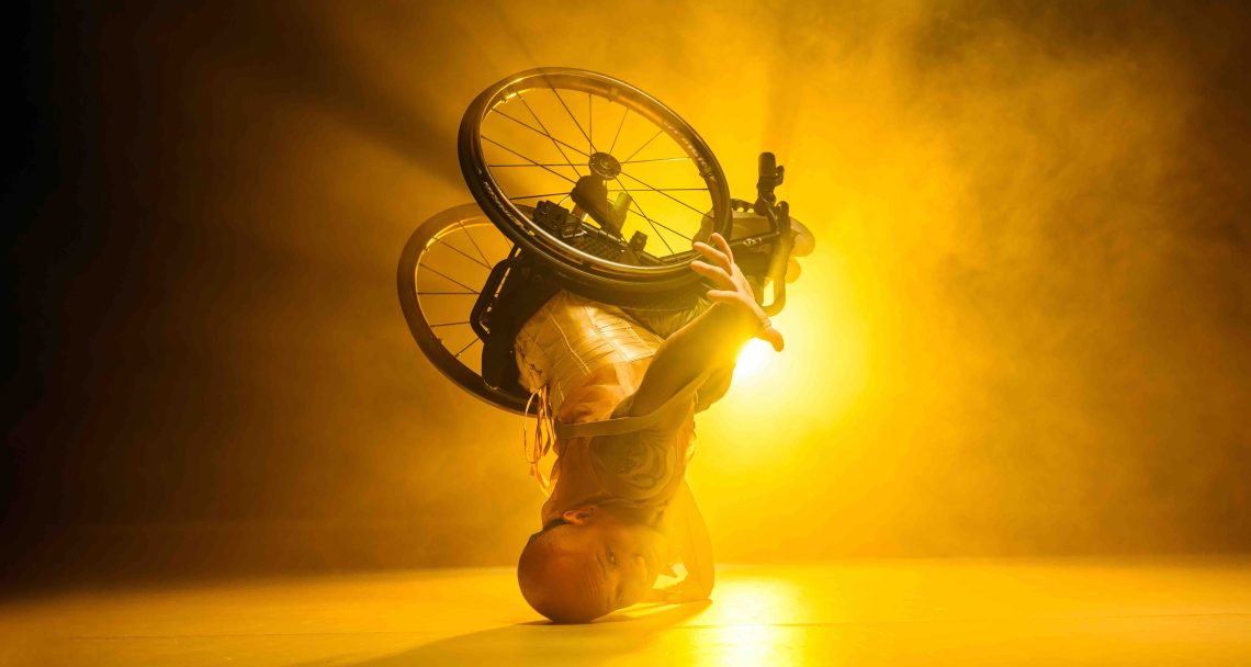A production image of a wheelchair dancer in an headstand.