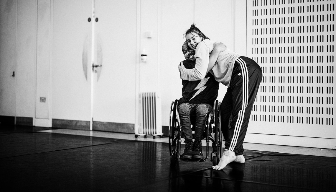 A black and white photo of two dancers hugging.