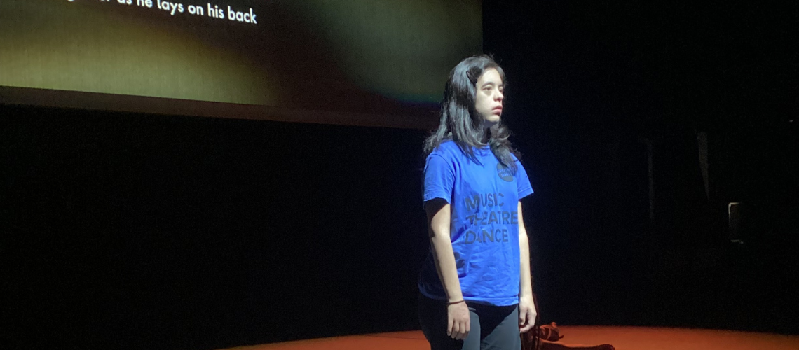 Angela on stage under stage lights.