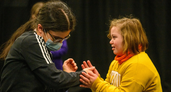 Two young disabled people hold their hands to one another