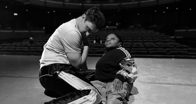 two dancers sit on the stage of an empty theatre