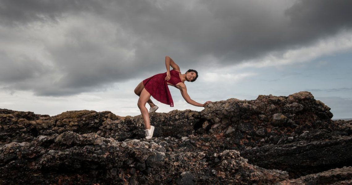 Dancer arches backwards on rugged rocks.