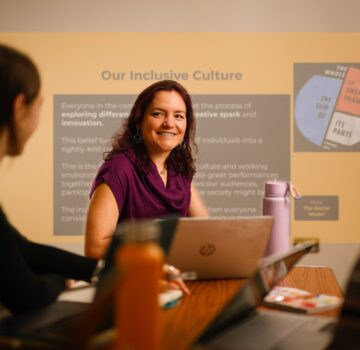 A white disabled woman in front of a powerpoint.