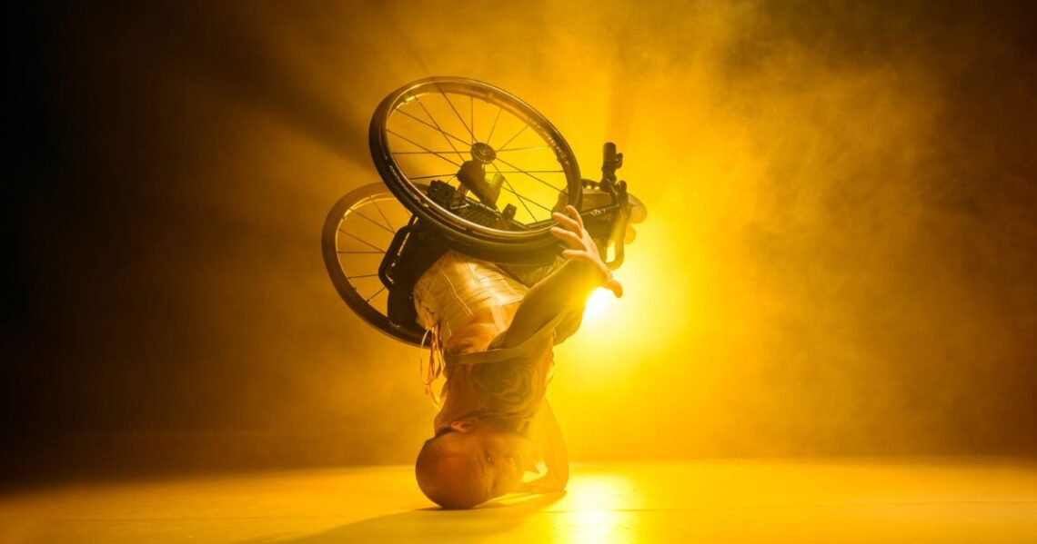 A production image of a wheelchair dancer in an headstand.